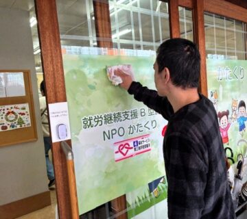 正面玄関のガラスを丁寧に拭き掃除をします。