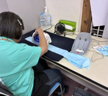 斉藤さんは、布ぞうりの鼻緒を作るためのアイロンがけに夢中です。